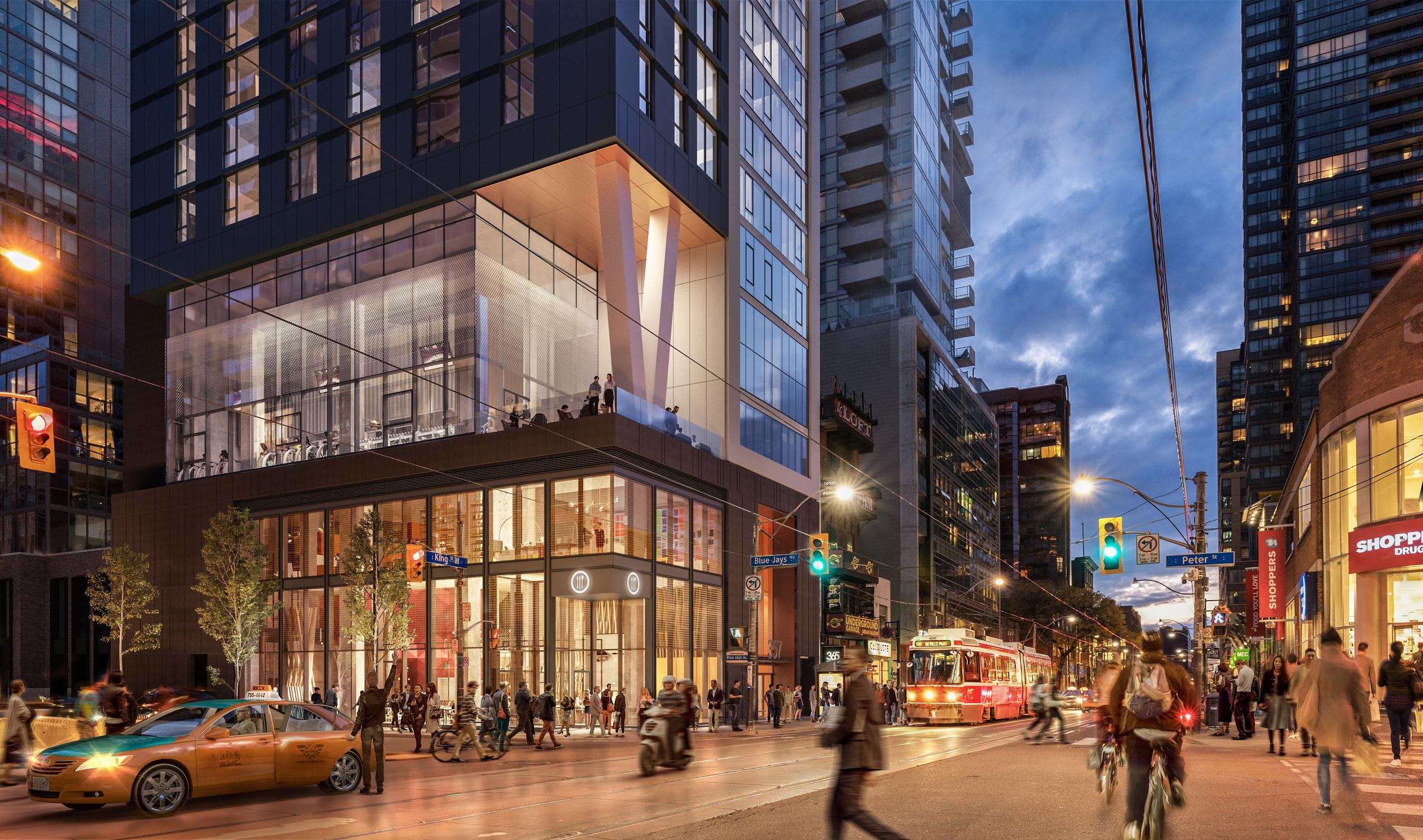 A bustling King Street at dusk showing the podium of 357 King with its glazed box base framed in black, and the glazed indoor/outdoor amenity between the podium and condo tower. two angled white columns on the amenity terrace support the upper tower.