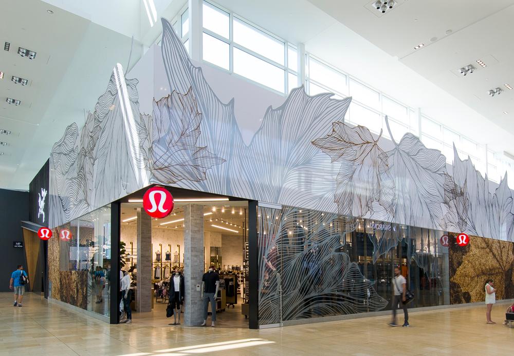 a mall storefront corner unit for Lululemon, made of glass with large white maple leaf decals
