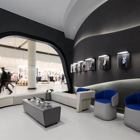 the seating area of the personalization zone at the Samsung Experience Store, one-of-a-kind phone cases in displays on the wall and a window with rounded edges shows the Eaton Centre hallway