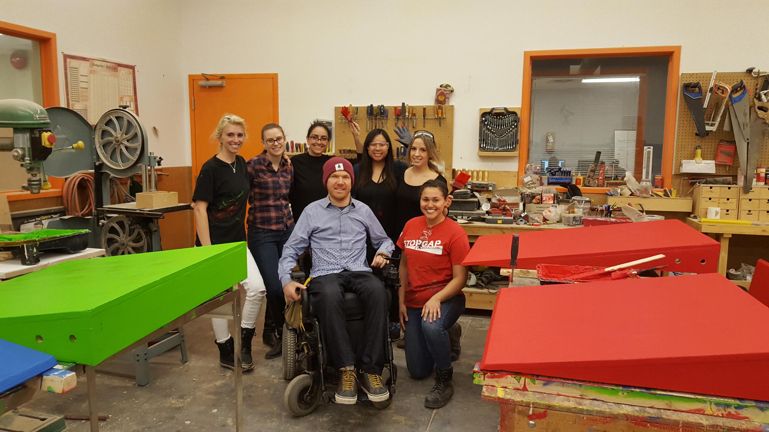 6 women pose with StopGap founder, Luke Anderson, surrounded by freshly painted ramps