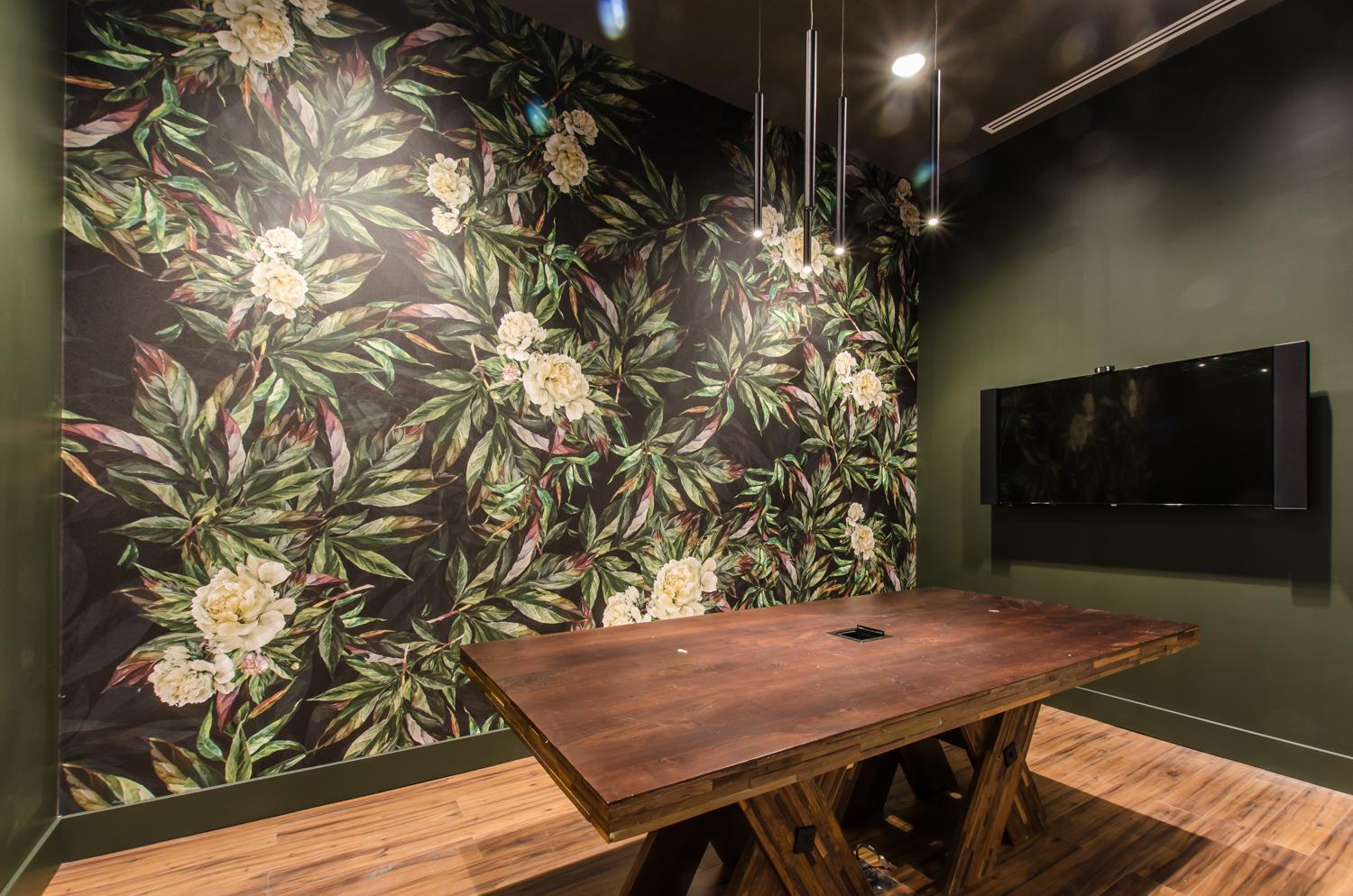a meeting room with forest green walls and a floral accent wall, wooden floors and wooden conference table