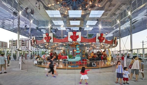 children and families around a carousel with a mirrored ceiling above