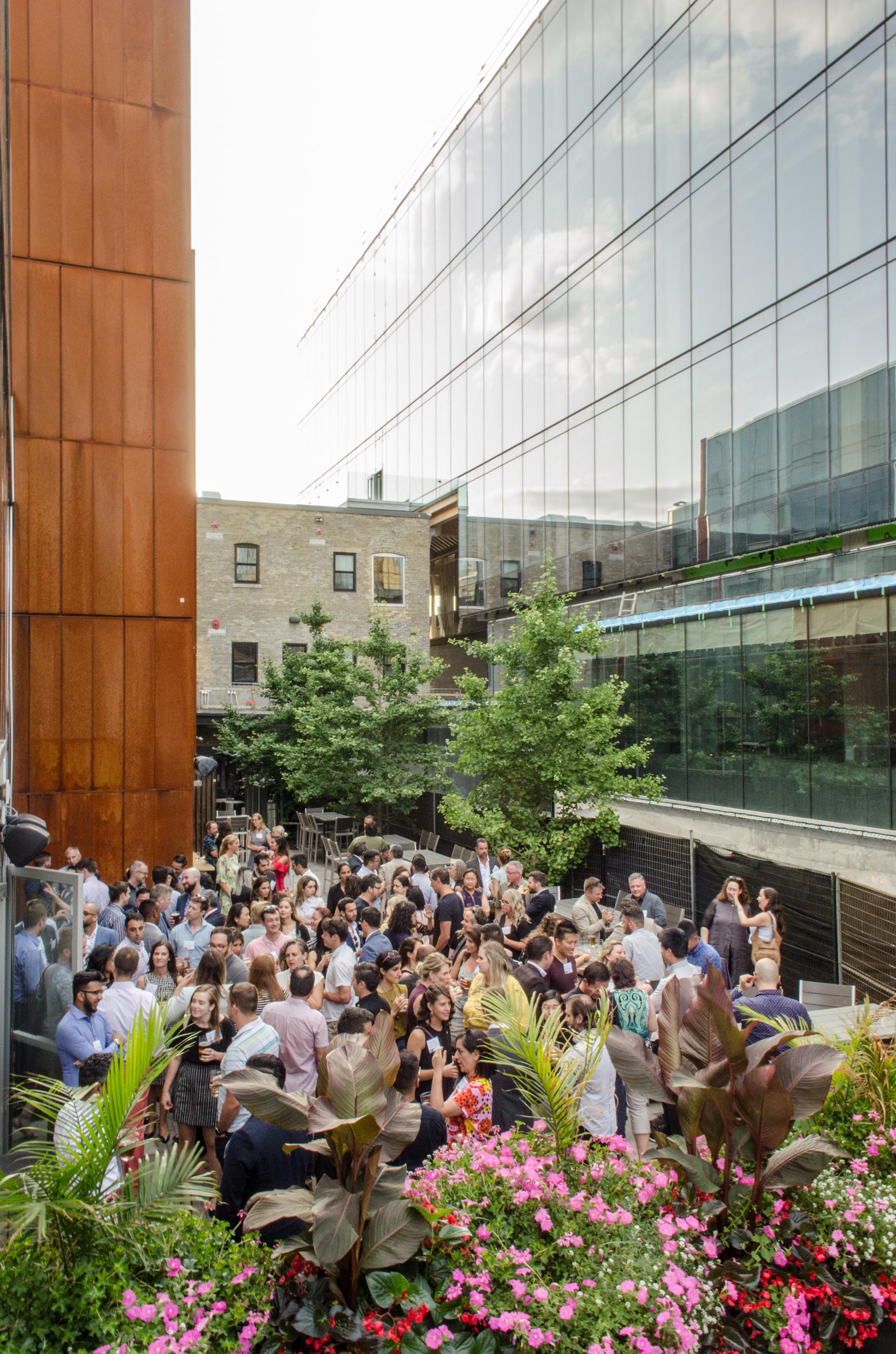 a crowd of people mingling at a networking event on a patio in between 60 and 80 Atlantic