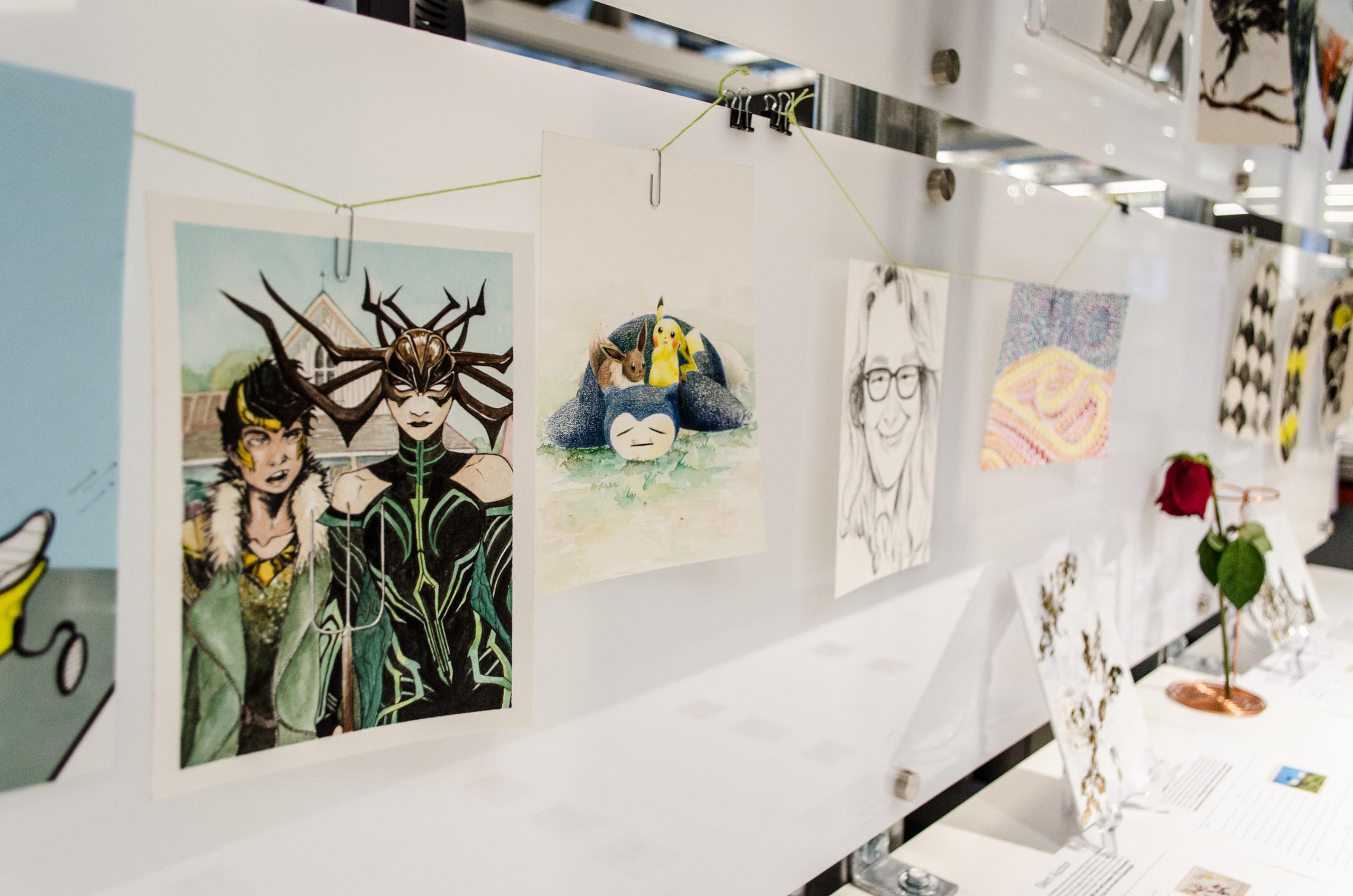 close up of art hung up in the Quadrangle studio showing cartoon paintings and sketches of Pokemon and Avengers characters