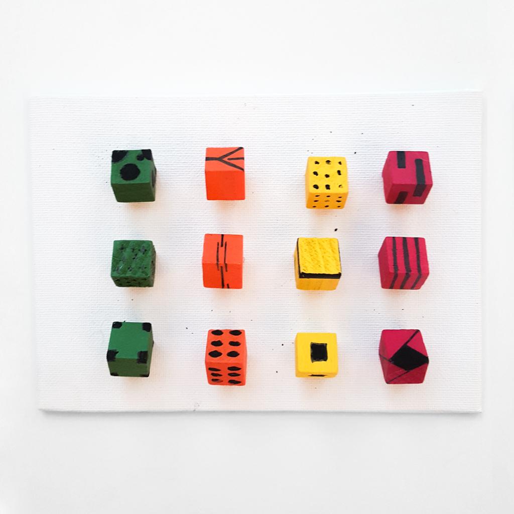 green, orange, yellow, and red cubes with different patterns protrude from white canvas