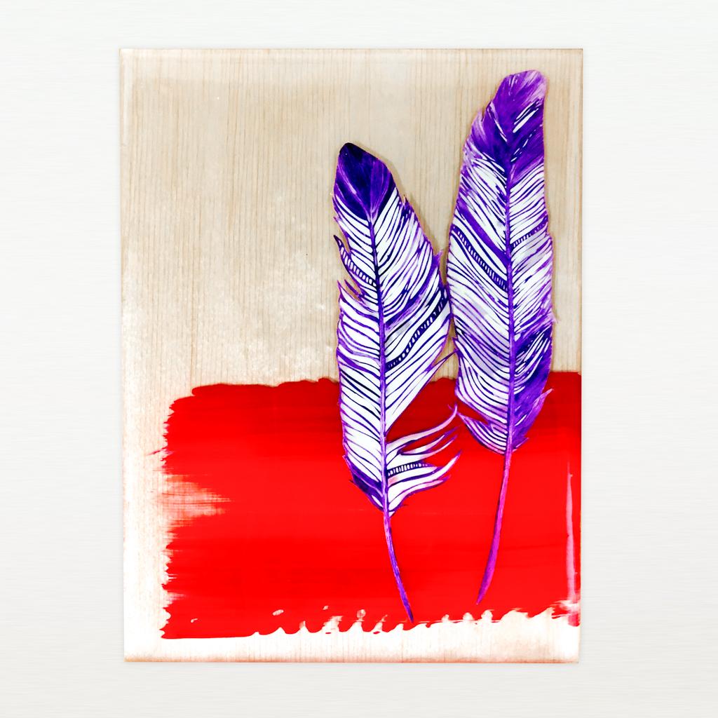 purple feathers and red swath of paint floating in resin on a wood panel