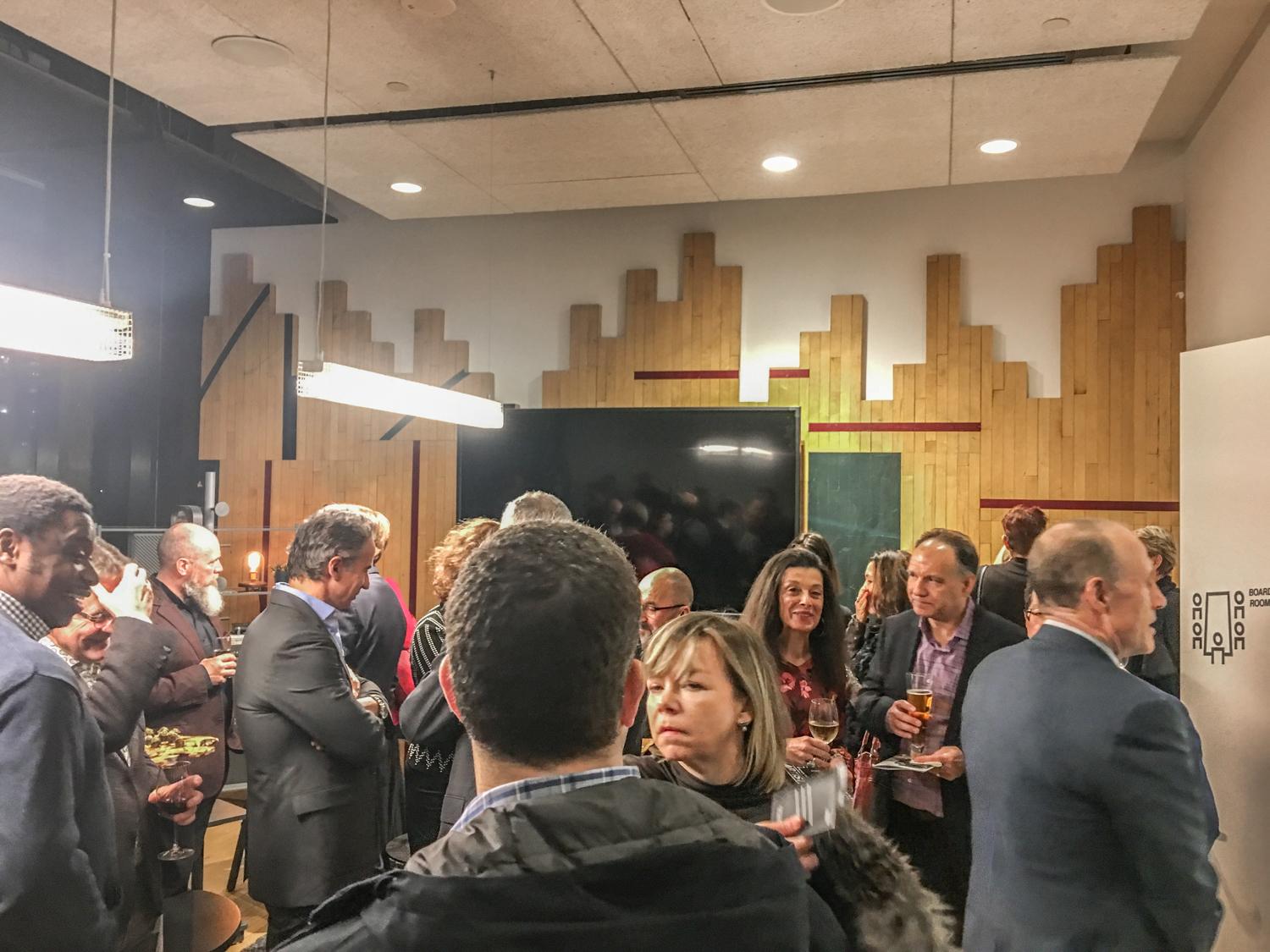 a crowd mingles in a boardroom that has repurposed gym flooring used as a wallcovering