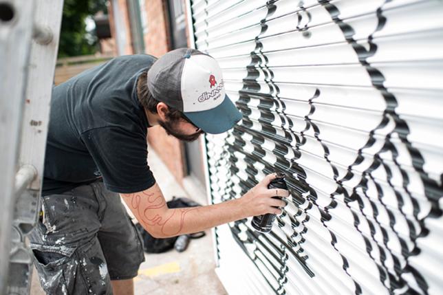 an artist spray-paints a mural