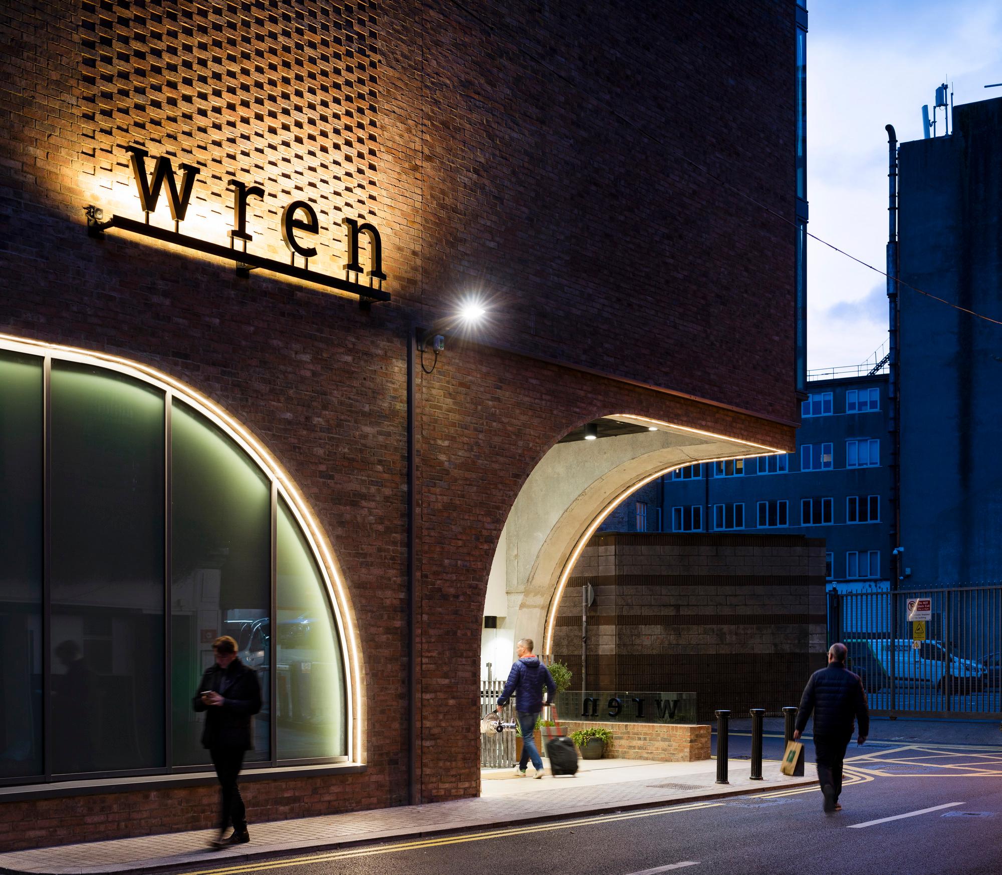 entrance to Wren Hotel at dusk, showing an arched cut out in the brick at the corner