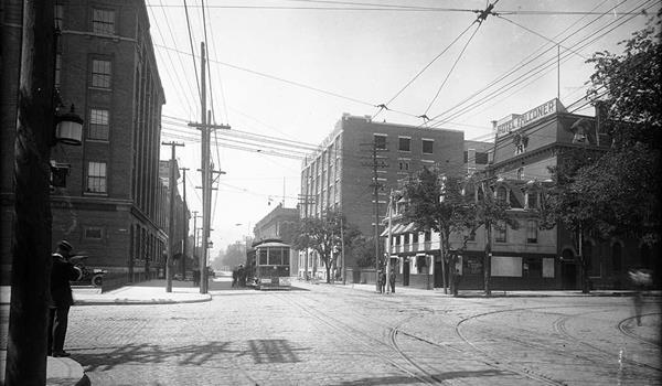black and white photo from the early 20th century of a factory building with a streetcar stopped in front