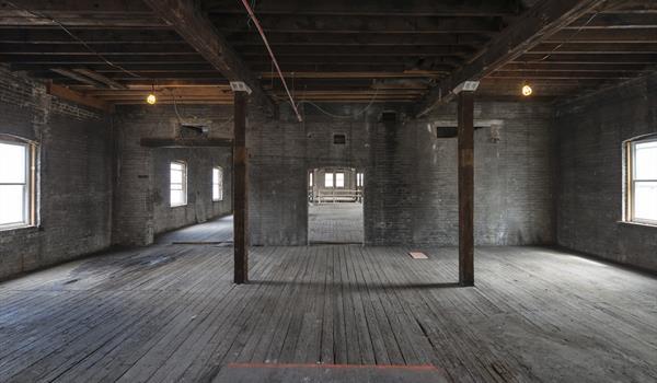Second floor interior with exposed brick walls and wood floor prior to construction