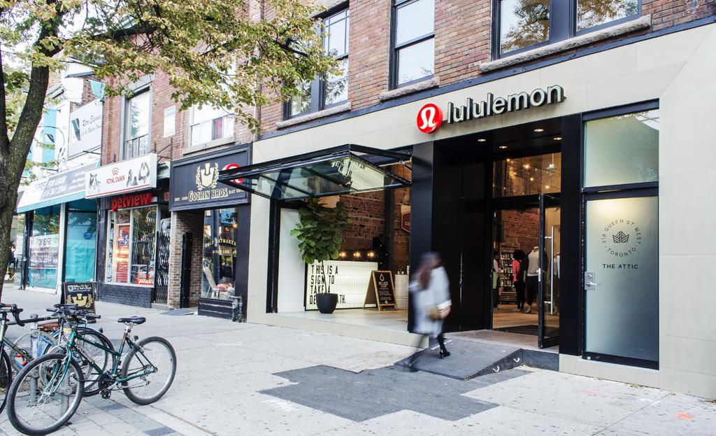 urban Lululemon storefront exterior with a shutter-style window wall opened up to the street